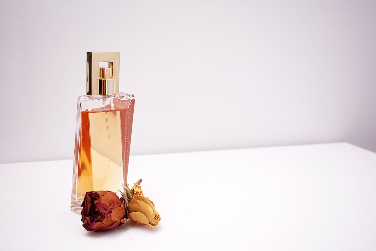 featured-images-02 Elegant glass perfume bottle with luxurious design placed next to dried flowers against a minimalistic white background.
